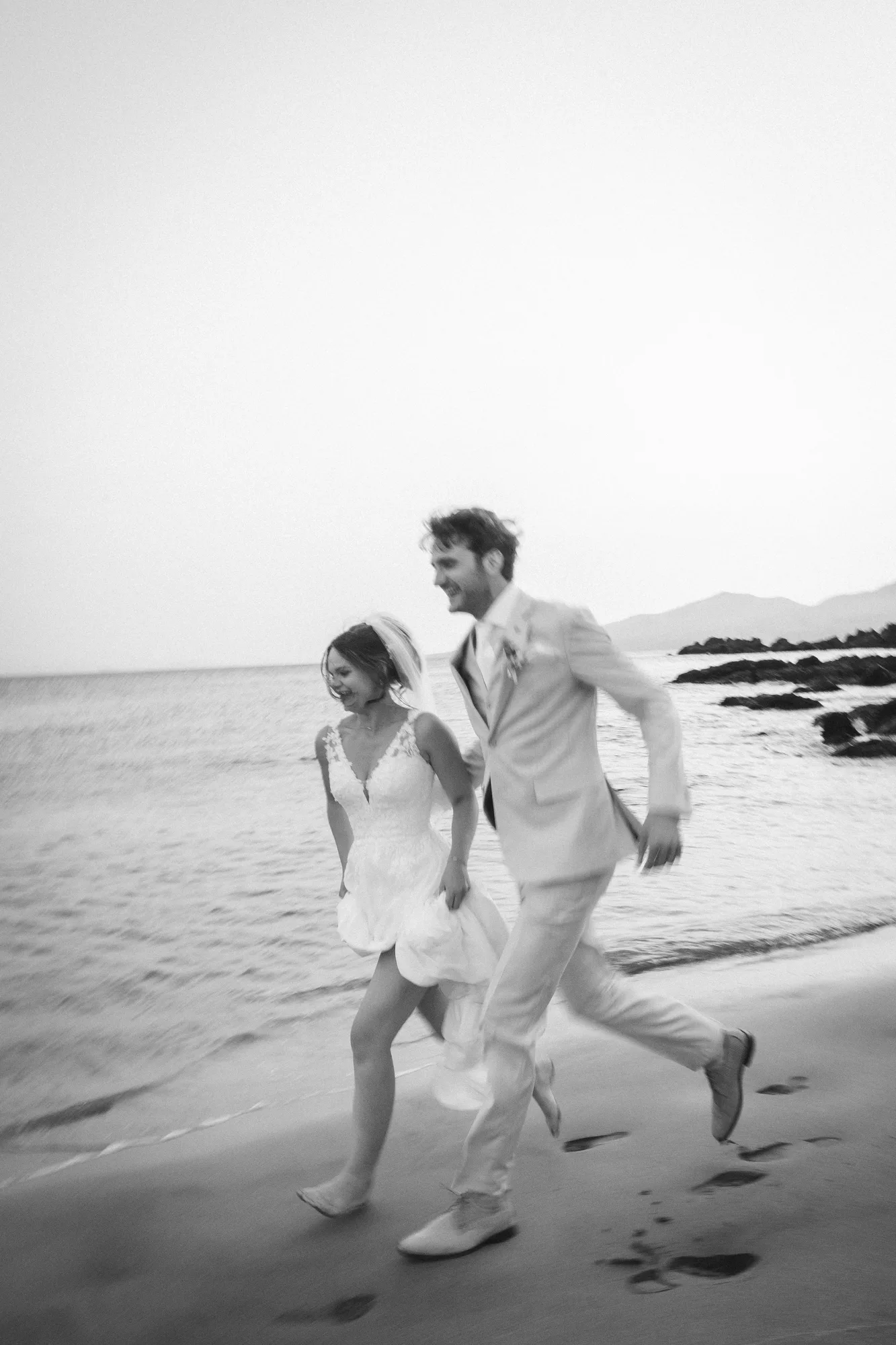 Suzanne y Tim corriendo por la playa en blanco y negro